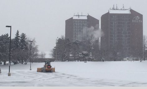 A snow plow is parked in the middle of a snowy field.