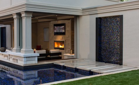 A pool with a fireplace and television in the background.