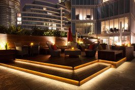 A patio with lights and furniture in the middle of it.