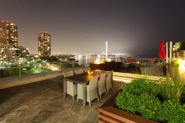 A large outdoor dining table with chairs and lights on the top of it.