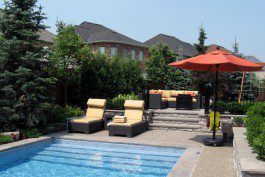 A backyard with a swimming pool and lounge chairs.