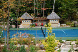 A tennis court in a wooded area with a gazebo.