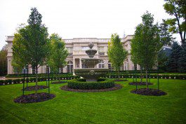 A large mansion with a fountain in front of it.