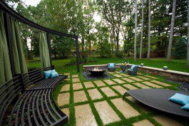 A backyard with a fire pit and green grass.