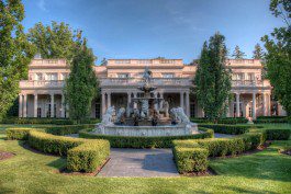 A large mansion with a fountain in the front yard.