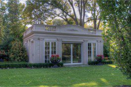 A white gazebo in the middle of a green lawn.