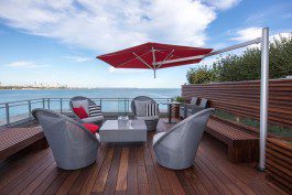 A deck with furniture and an umbrella overlooking the water.