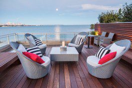 Wicker furniture on a wooden deck overlooking the water.