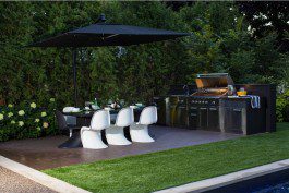 An outdoor kitchen with a table and chairs and an umbrella.