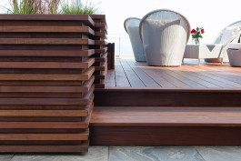 A wooden deck with steps and stairs leading to the patio.