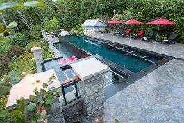 A pool with a waterfall and a large deck.