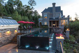 A pool with an outdoor fireplace and fire pit.