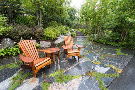 Two wooden chairs and a table on the side of a stone path.