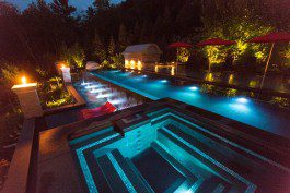 A pool with lights on and lit up at night.