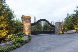 A driveway with a gate and stone pillars.