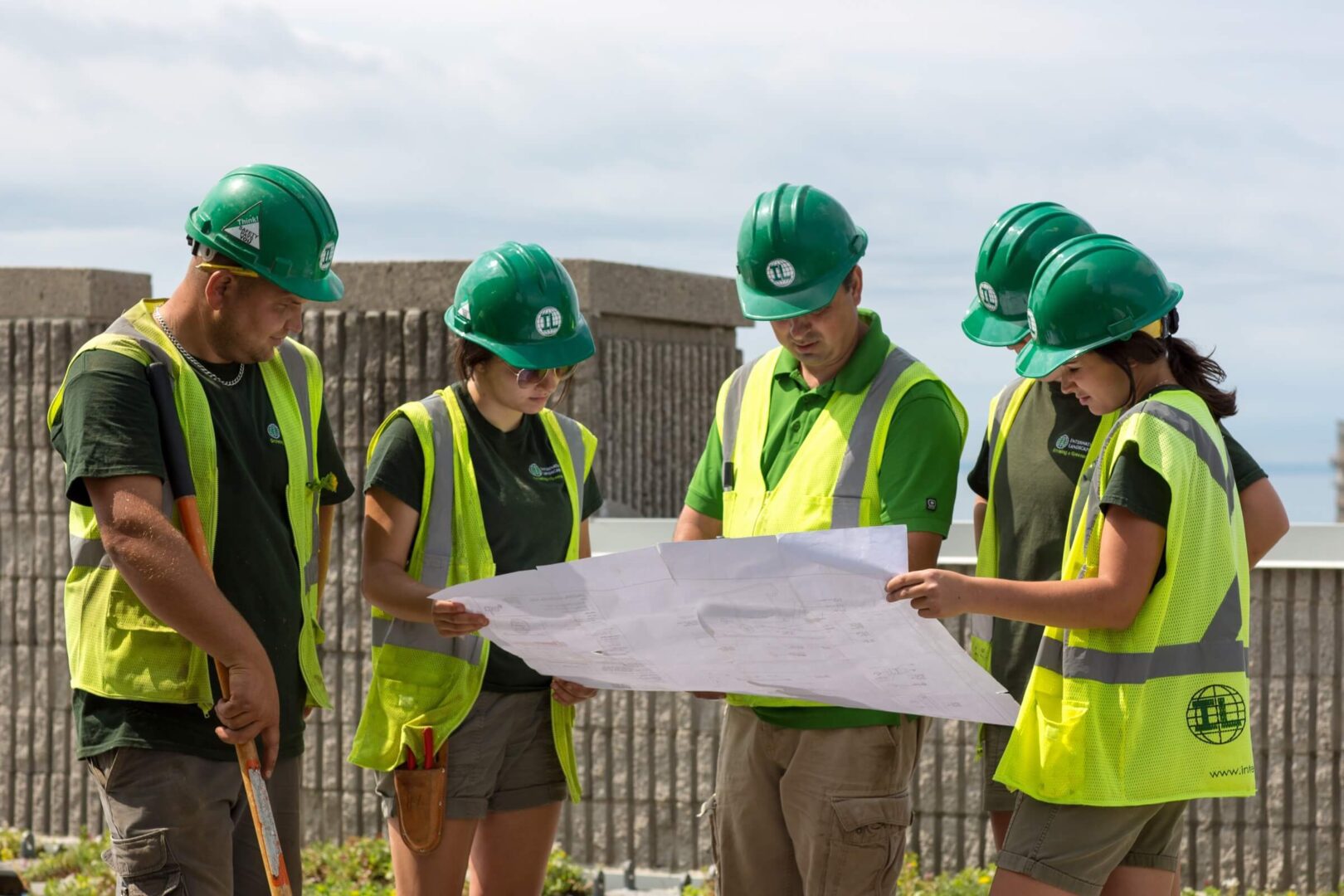 A group of people in green vests and hard hats.