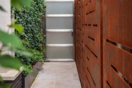 A walkway with wooden doors and plants growing on it.