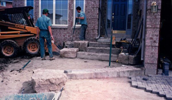 Two men working on a building with stone steps.