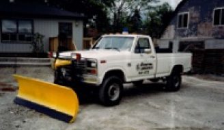 A white truck with a plow in the back.