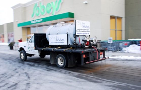 A truck driving down the street in front of a store.