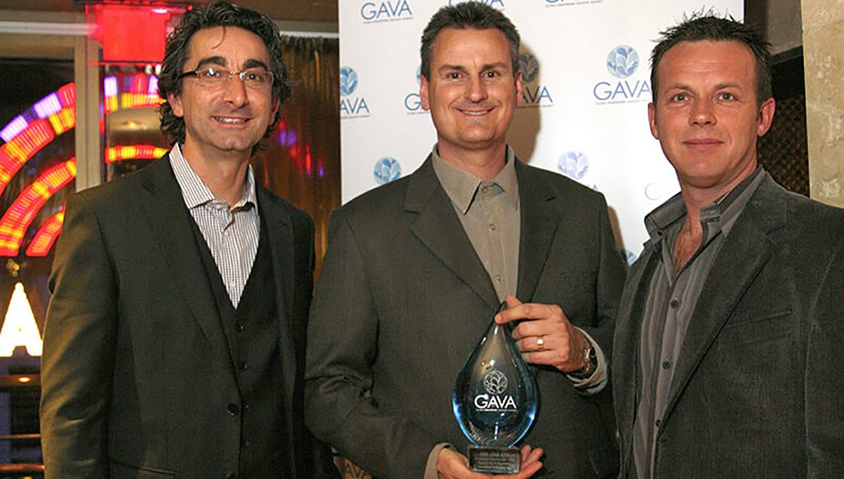 Three men in suits and ties holding a plaque.