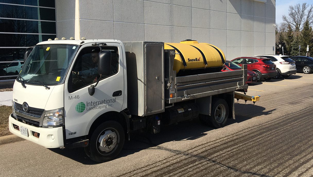 A truck with a yellow barrel on the back of it.