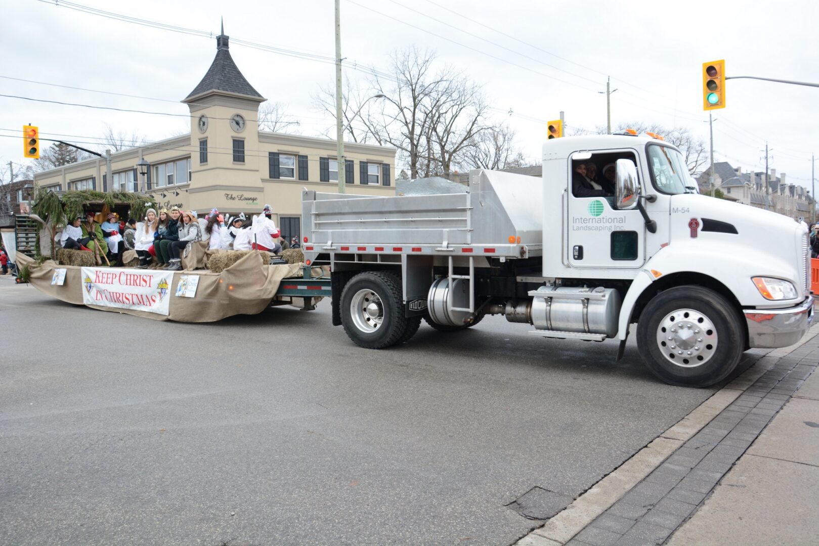 A white truck driving down the street with people in front of it.